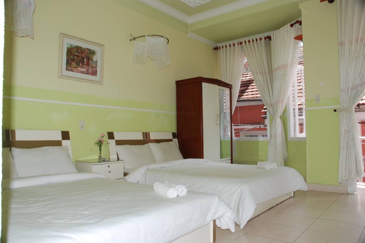A hotel room with two beds, a nightstand, a mirror, and a window with curtains.