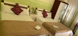 A hotel room with two beds, each with a brown bedspread and a rolled towel. There are decorative pillows with red patterns, a bedside table with a lamp, and a mirror on the wall. - Bich Khue Hotel (Lam Vien - Da Lat)
