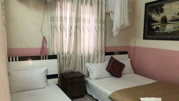 A hotel room with two beds, a nightstand, a small cabinet, and a painting on the wall.
