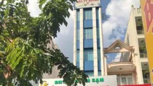 Un hotel con un letrero que dice "KOVY HOTEL" y otro que dice "VAN PHO". Hay un cartel grande con texto parcialmente oculto.