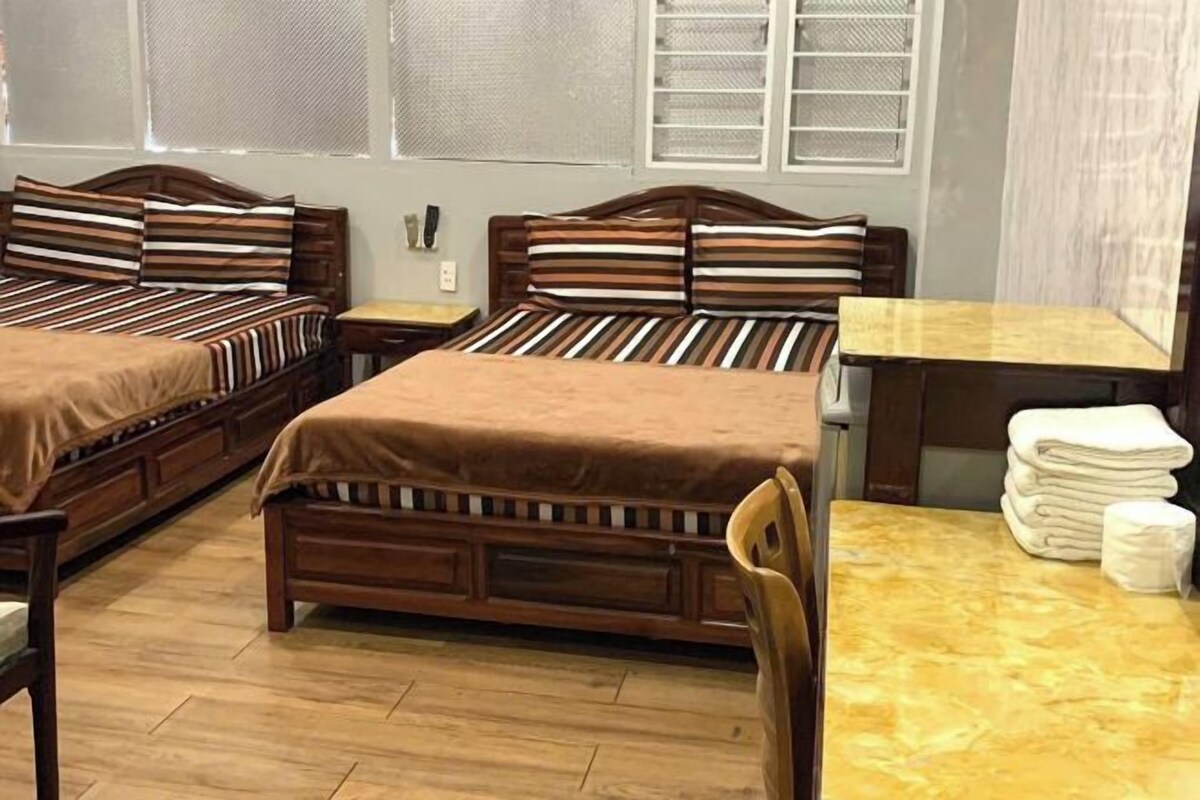 Una habitación de hotel con dos camas de madera, una mesita pequeña y una silla.