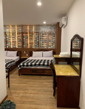 A bedroom with two beds, a wooden dresser, a mirror, and a window with a view of a brick wall. - Hoang Yen Nhi Hotel (Ho Chi Minh City)