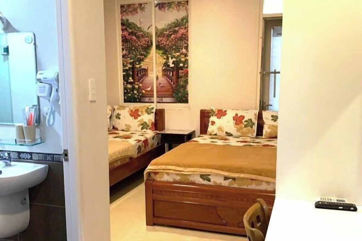 A bedroom with a bed, a nightstand, a mirror, a sink, and a window with a view.