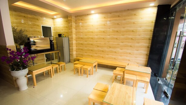 A modern kitchen with wooden panel walls, a built-in stove, and a seating area with wooden tables and benches. - Phuc Dang Huy Hotel (Xuan Huong - Da Lat)
