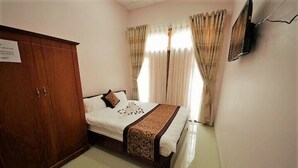 A bedroom with a bed, a wardrobe, curtains, and a television. - Phuc Dang Huy Hotel (Xuan Huong - Da Lat)