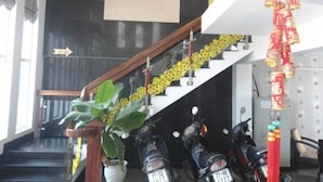 A staircase with a chandelier, a logo on the wall, and a red decoration.