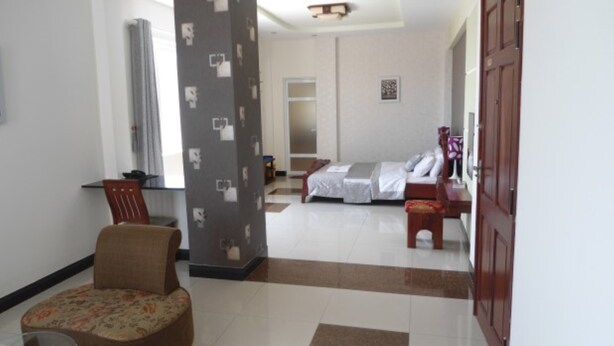 A hotel room with a bed, a desk, a chair, and a large pillar with a patterned design.