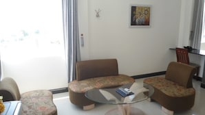 A living room with a sofa set, a glass coffee table, and a dining area with a chair and table.