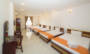 A hotel room with four single beds, a desk, a chair, and a mirror. - House Land Hotel Da Nang (Da Nang)