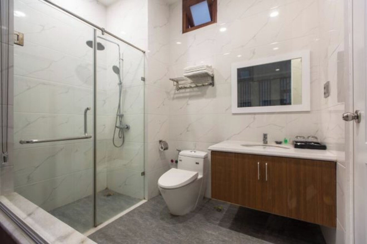 A modern bathroom with a glass shower enclosure, a toilet, and wooden cabinets.