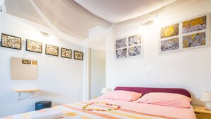 Een hotelkamer met een bed, kussens, een nachtkastje, een lamp en kunst aan de muur.