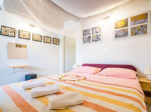 Une chambre d’hôtel avec un lit, des oreillers, une table de chevet, une lampe et des œuvres d’art accrochées aux murs.
