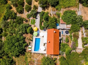 Oversigtsbillede af en ejendom med swimmingpool, udendørs møbler og en bygning med rødt tag.