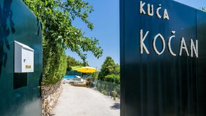 Een poort met een bord waarop 'KUČA KOČAN' staat.