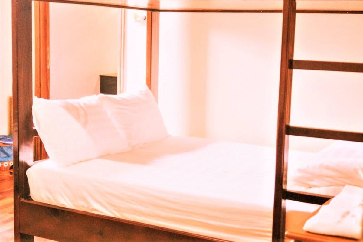 A single bed with a wooden frame and white bedding in a room with a wooden floor.