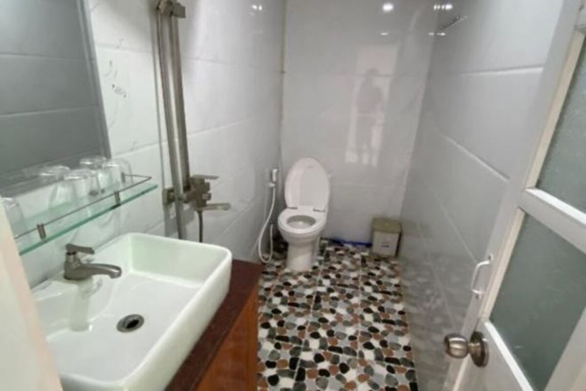 Ein kleines, kompaktes Badezimmer mit einem weißen Waschbecken, einer Toilette und einer Duschkabine.