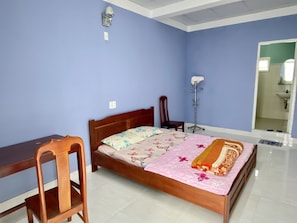 Une chambre à coucher avec un lit en bois, une chaise, un bureau et une lampe sur pied.