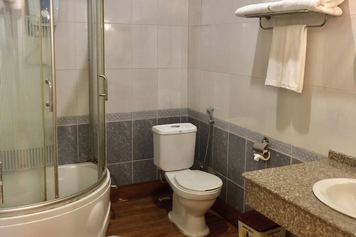 Ein Badezimmer mit einer gläsernen Duschkabine, einer Toilette und einem Waschbecken mit Marmorplatte.