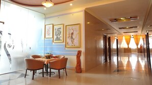A hotel lobby with a dining area, framed artwork on the walls, and a corridor leading to another section. - Thang Loi Hotel (Ho Chi Minh City)
