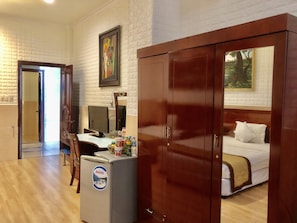 Une chambre d’hôtel comprenant un lit, un bureau avec un ordinateur, un réfrigérateur et une armoire en bois.