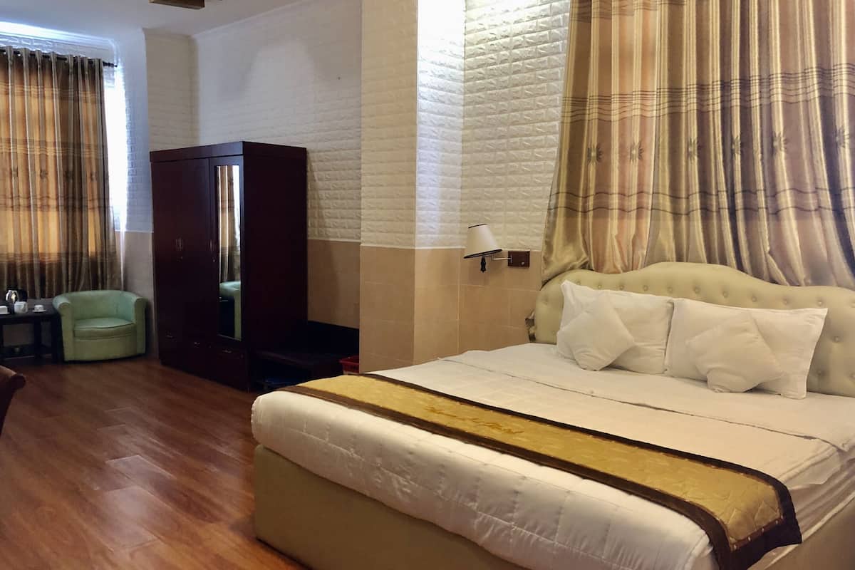 Une chambre d’hôtel avec un lit, une chaise, une armoire et une table de chevet.