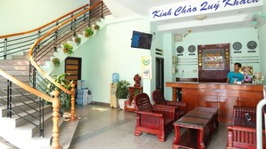 A hotel lobby with a staircase, reception desk, and seating area. - Phu Gia Hotel (Phu Thuy)