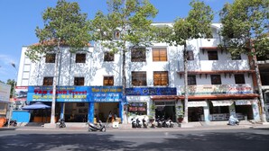 A multi-story building with various shops on the ground floor. - Phu Gia Hotel (Phu Thuy)