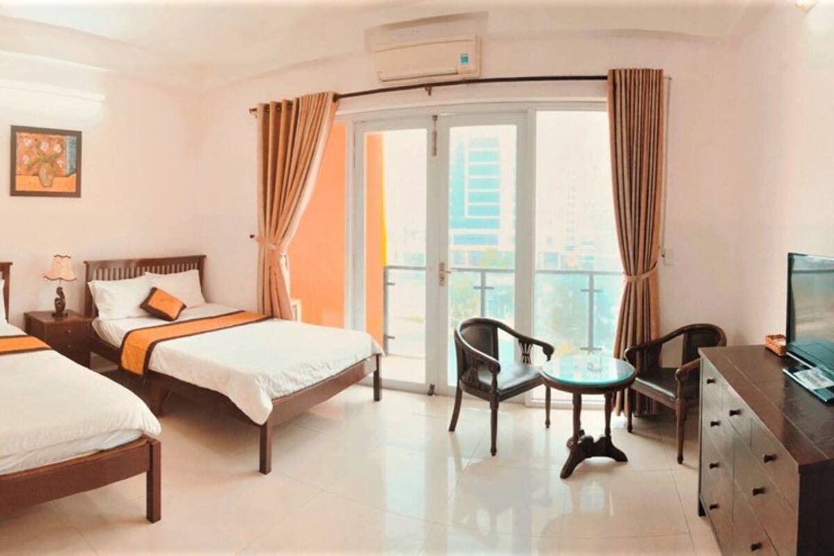 A hotel room with two beds, a TV, a small table, and a chair.