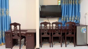 Ein Wohnzimmer mit Fernseher, Holzmöbeln und blauen Vorhängen.