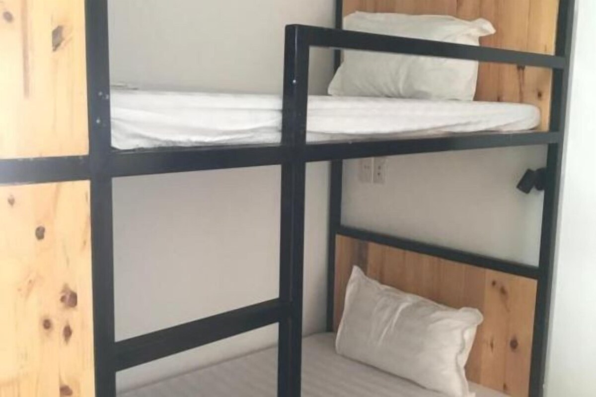 Een stapelbed met houten frame en witte beddengoed.