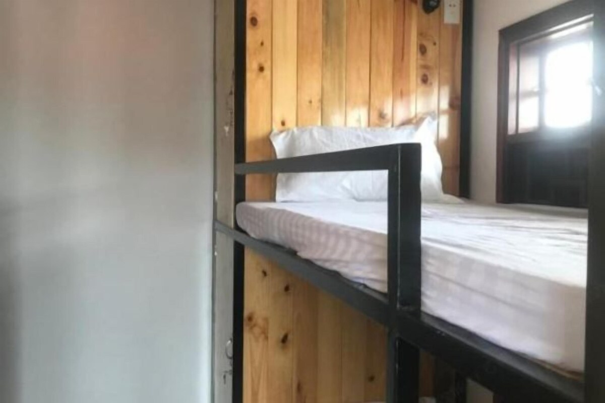 Een stapelbed met een houten hoofdbord en witte beddengoed.
