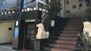 A hotel entrance with a staircase leading to the entrance, potted plants, and a sign with Vietnamese text. - Thao Trang Hotel Dong Hoi (Dong Hoi)