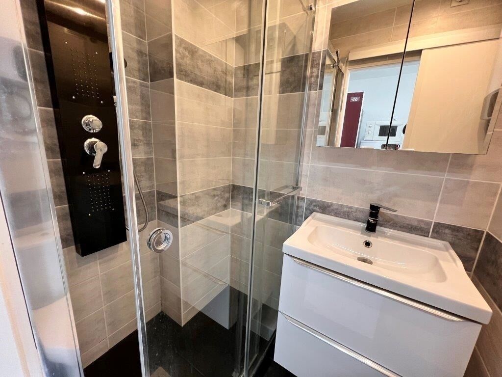 Un baño moderno con cabina de ducha de vidrio, un lavabo blanco y un espejo sobre él.