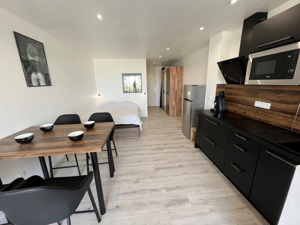 Une cuisine moderne équipée d’un four à micro-ondes, d’une cuisinière et d’un réfrigérateur. Un coin repas est aménagé avec une table et des chaises en bois.
