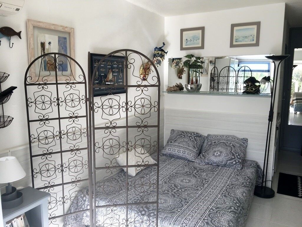 Un dormitorio con una colcha estampada, un separador de metal y una mesita de noche con una lámpara.