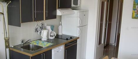 A compact kitchen with dark cabinets, a microwave, a coffee maker, and a dishwasher.