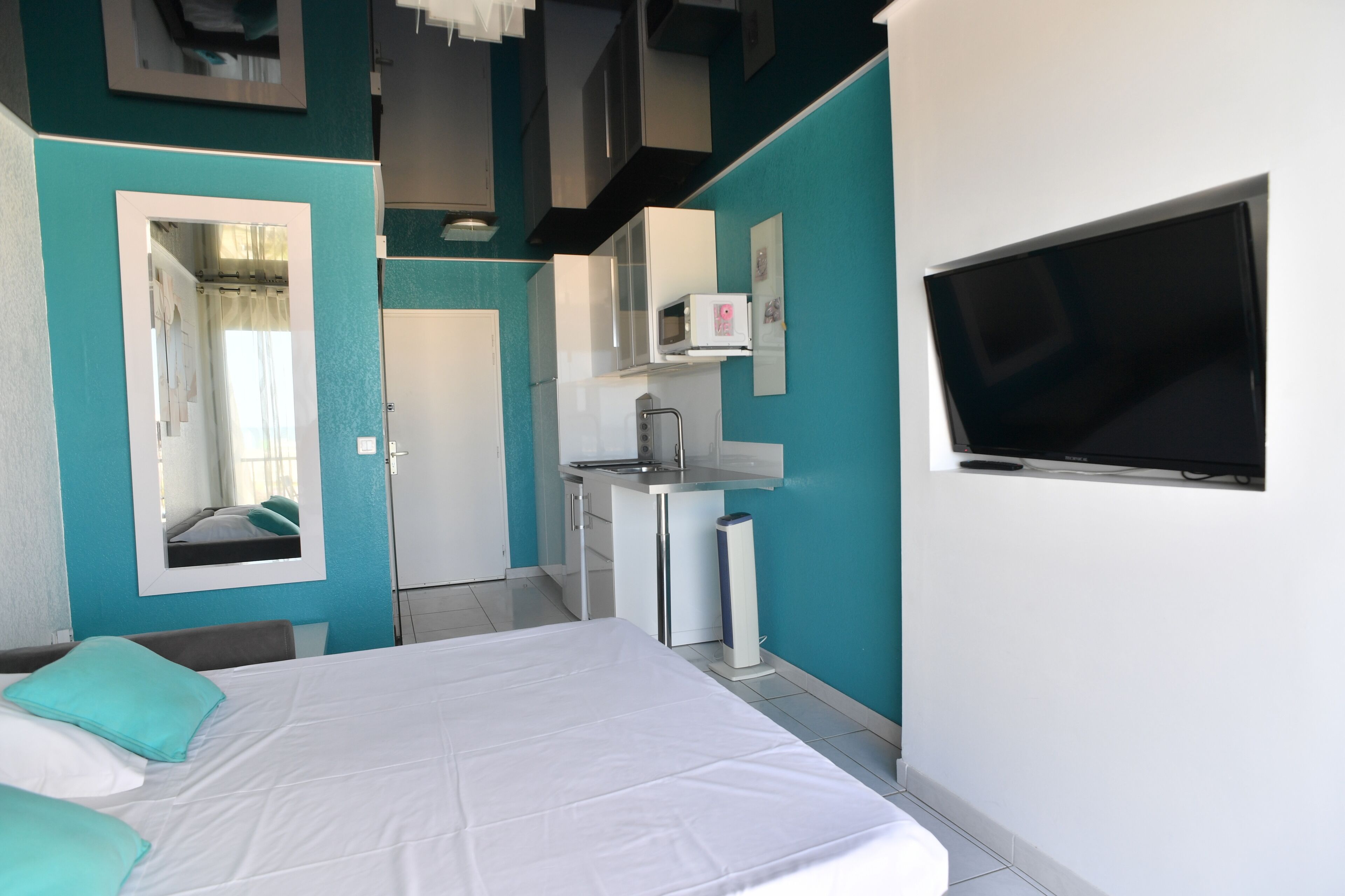 Une chambre avec un lit, une télévision, un four à micro-ondes et une petite kitchenette.