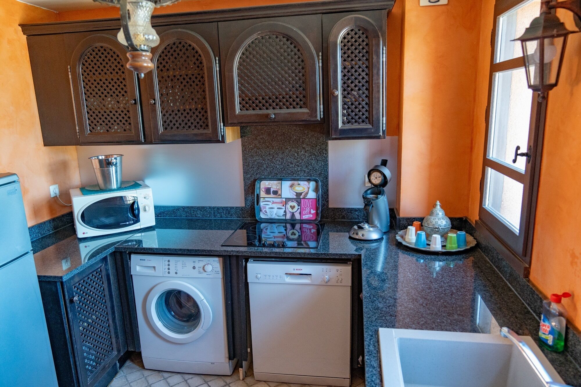 A compact kitchen with a washing machine, microwave, and a coffee maker.