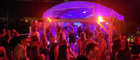 A crowded outdoor event with a covered stage and a crowd of people.