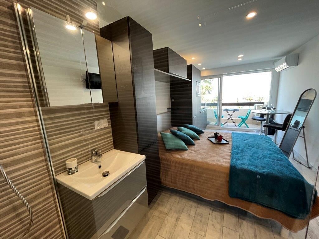 A modern bedroom with a bed, a sink, and a balcony with a table and chairs.