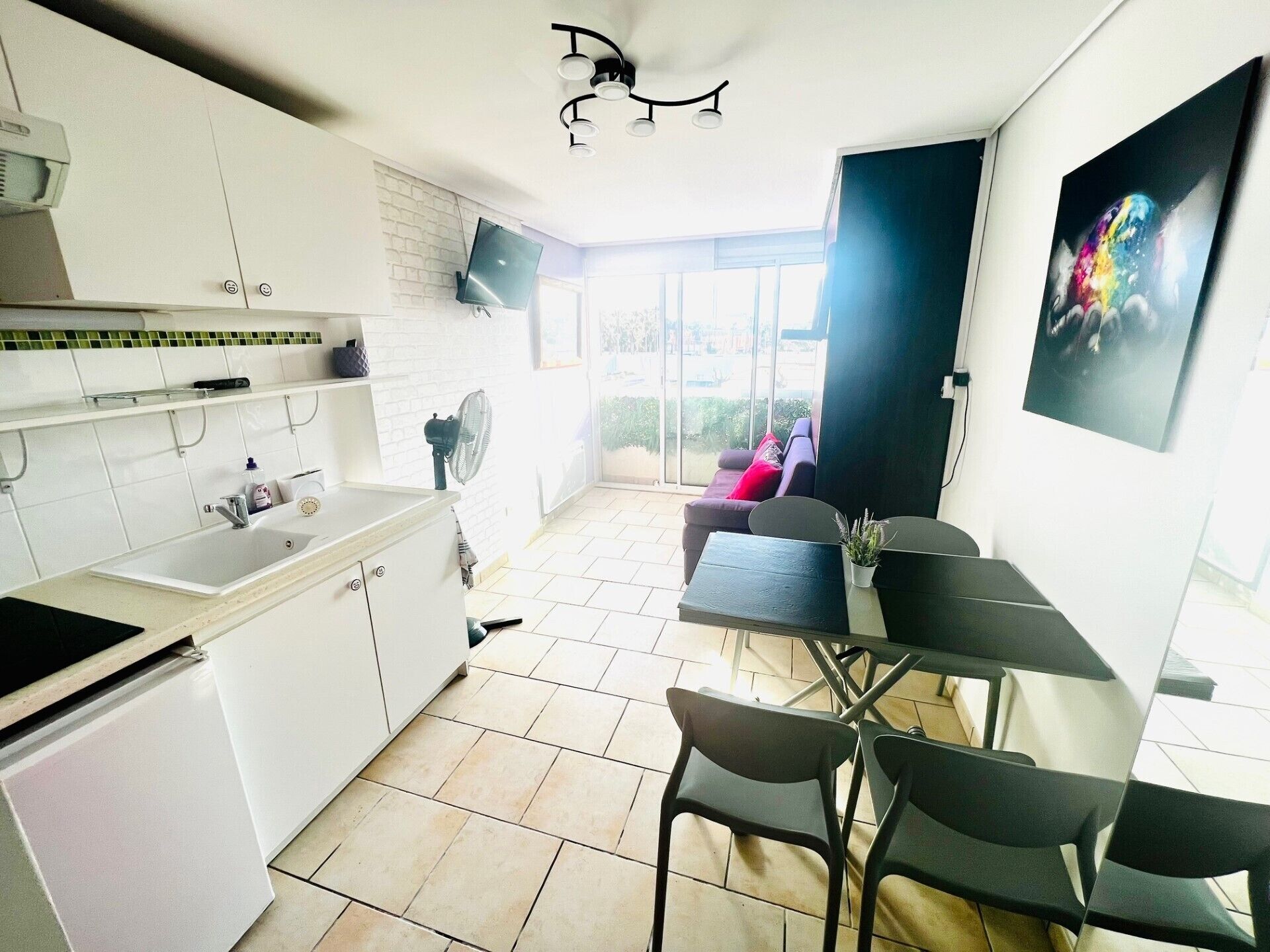 A compact kitchen with white cabinets, a sink, and a dining area with a table and chairs.