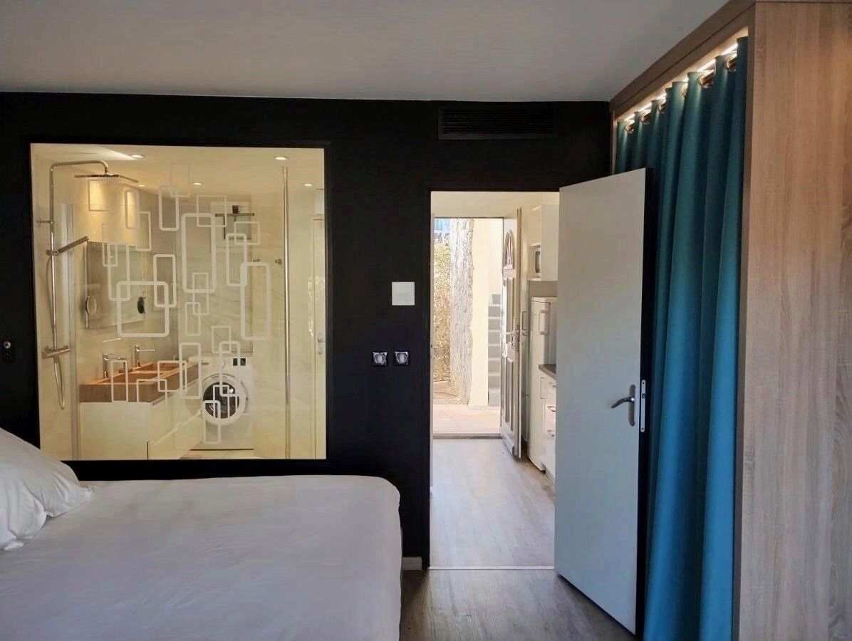 A modern hotel room with a large bed, a walk-in closet, and a view of the outdoor area.