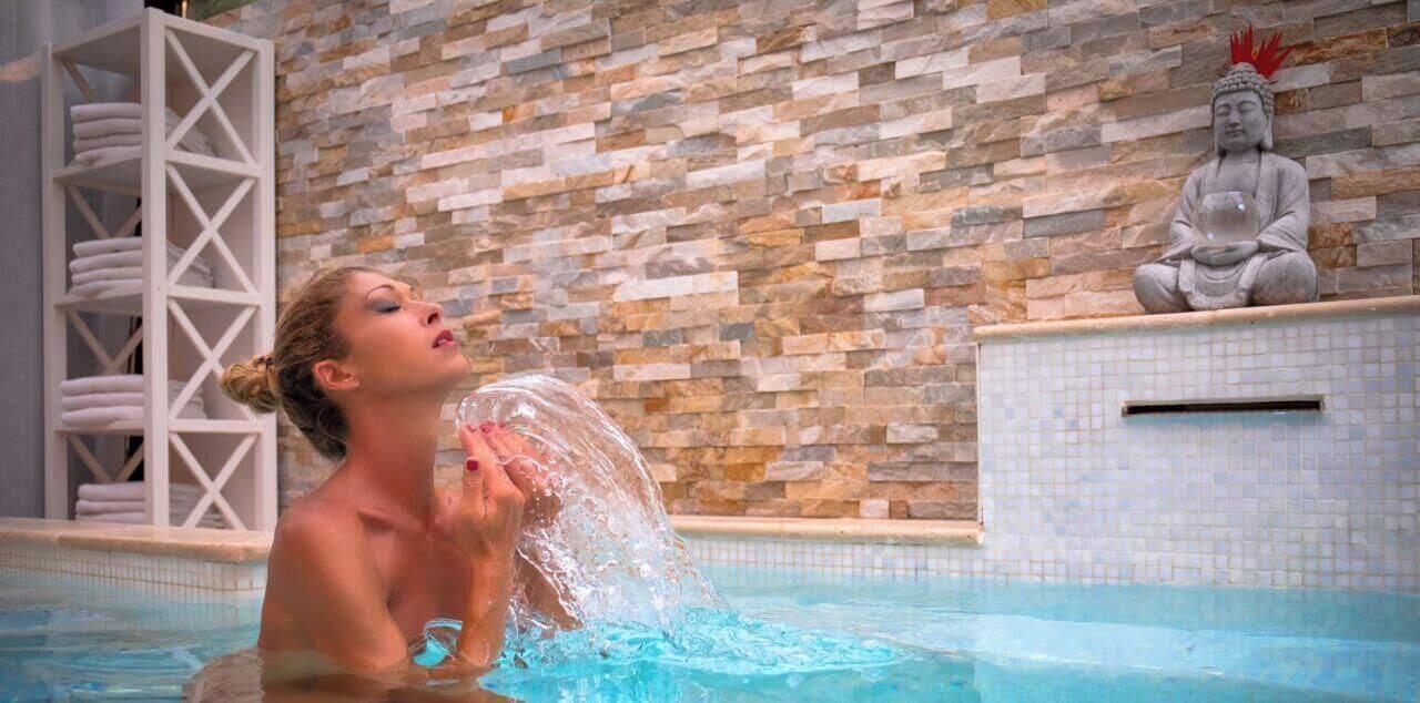 A woman in a swimming pool with a Buddha statue in the background.
