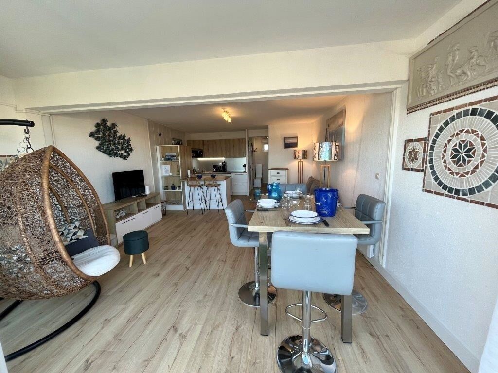 Ein modernes Wohnzimmer mit Essbereich, einer Küche im Hintergrund und einem großen Wandkunstwerk.