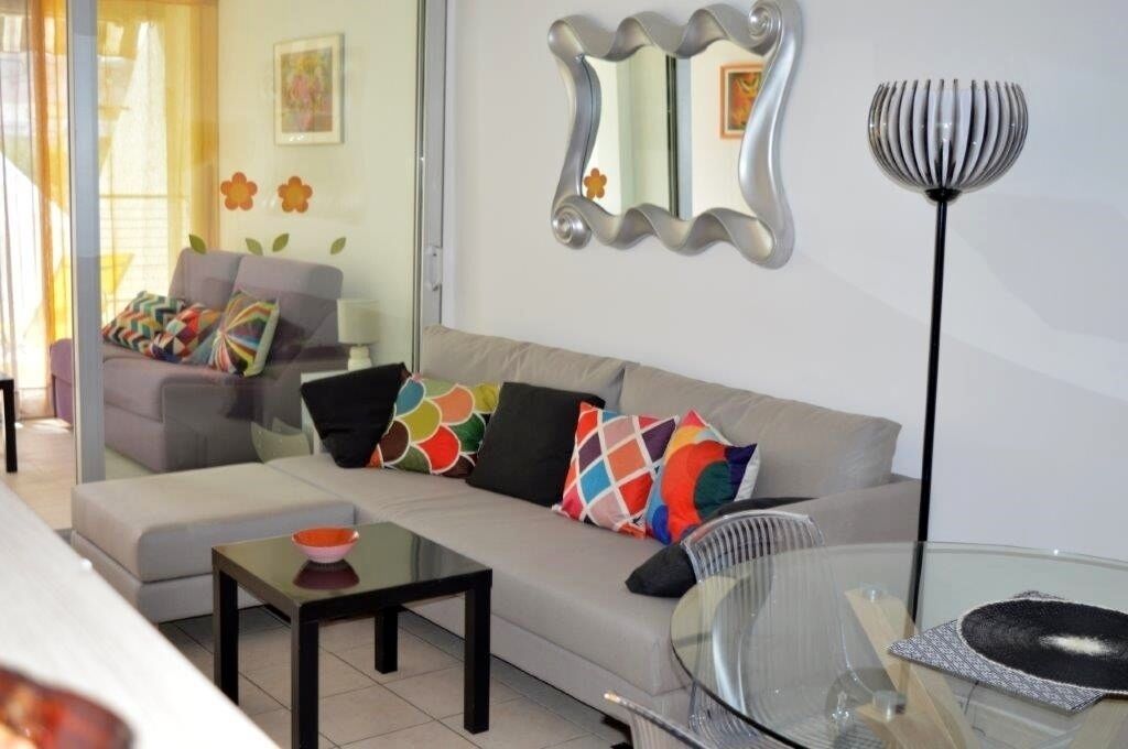 A modern living room with a sofa, a glass coffee table, and a floor lamp.