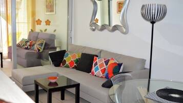 A modern living room with a sofa, a glass coffee table, and a floor lamp.