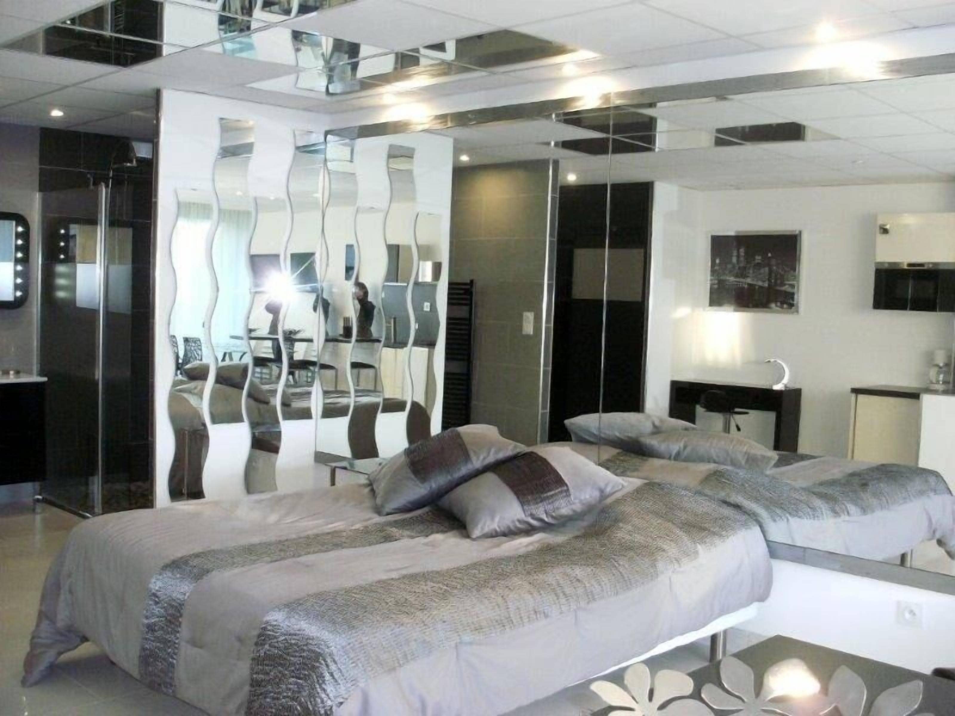 A modern hotel room with a large bed, a desk, and a mirror.