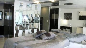 A modern hotel room with a large bed, a desk, and a mirror.