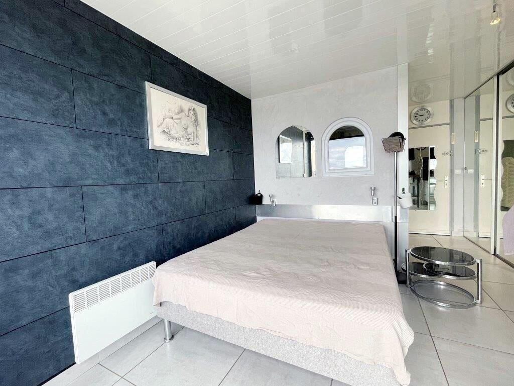 Un dormitorio moderno con una cama grande, una pared de acento oscura y una obra de arte enmarcada.