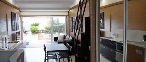 A modern kitchen with a dining area, large windows, and a view of the outdoors.